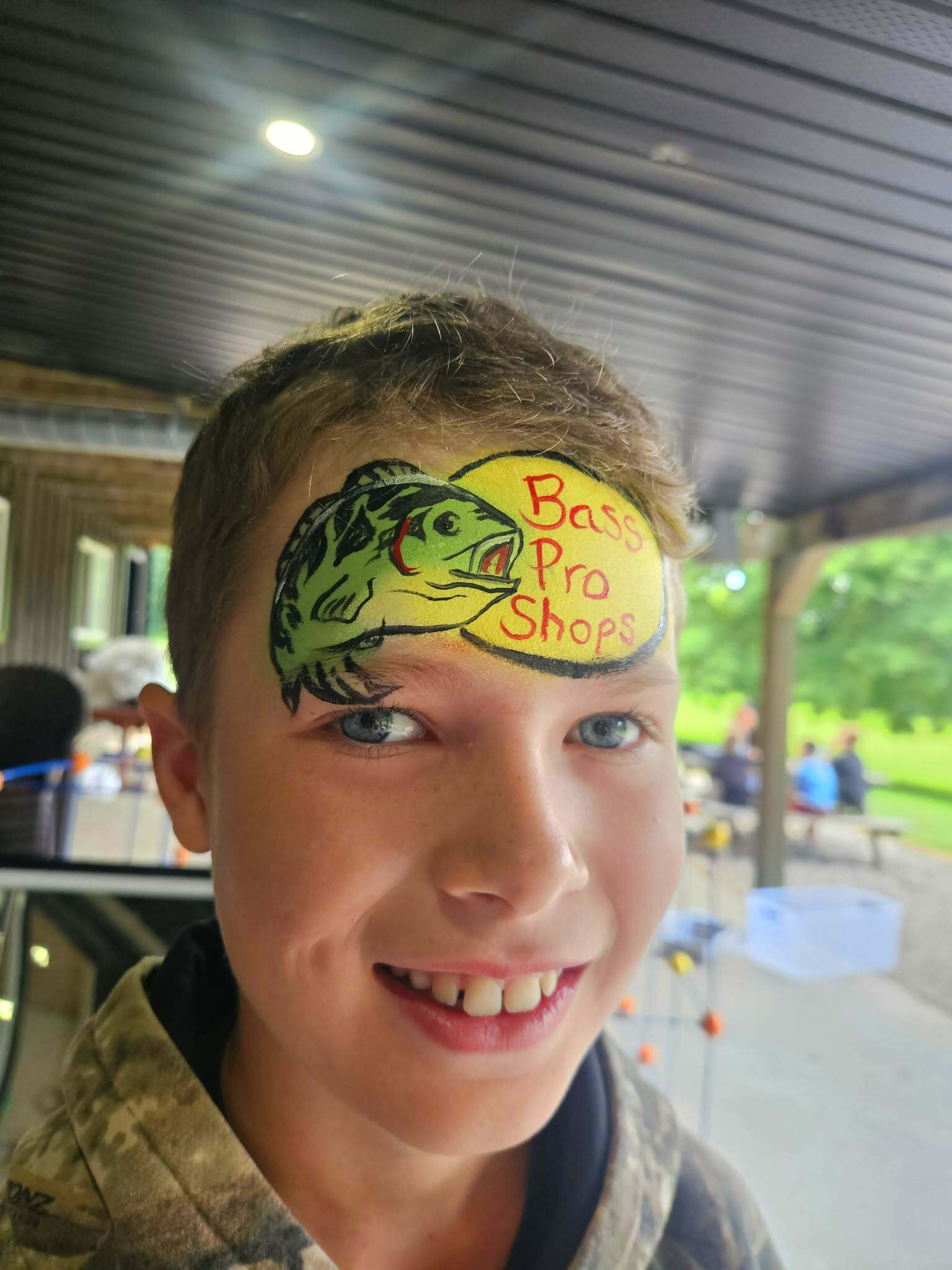 Boy with a leaping bass fish and Bass Pro Shops logo painted on his forehead