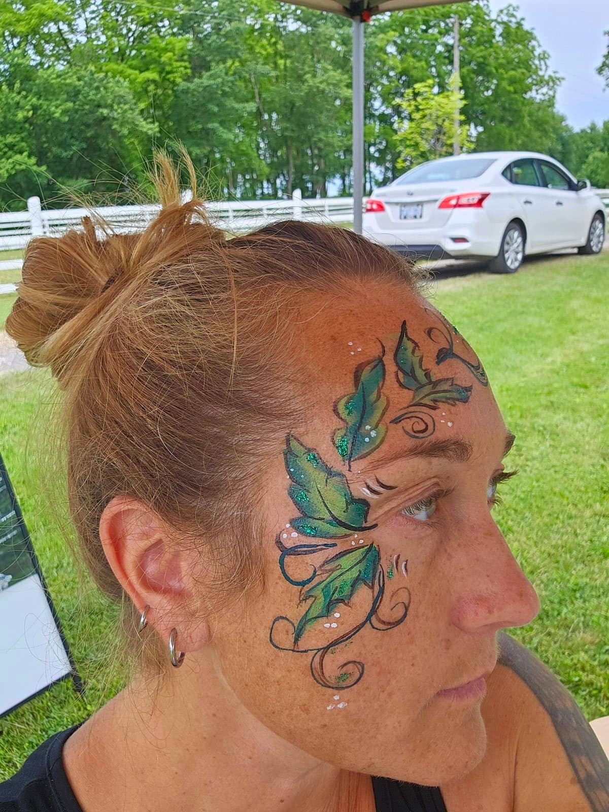 Woman with green fairy leaves and vines painted around her eyes