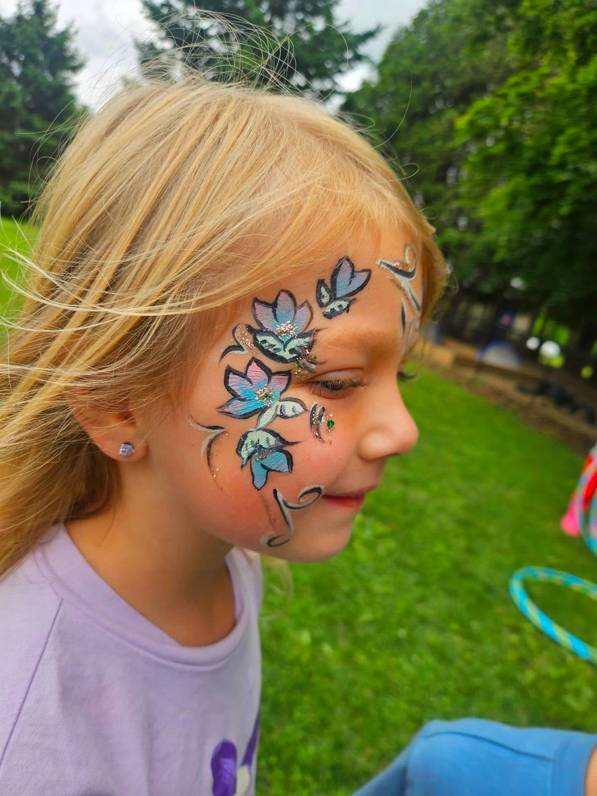 Girl with pastel blue and pink flowers painted around her eye