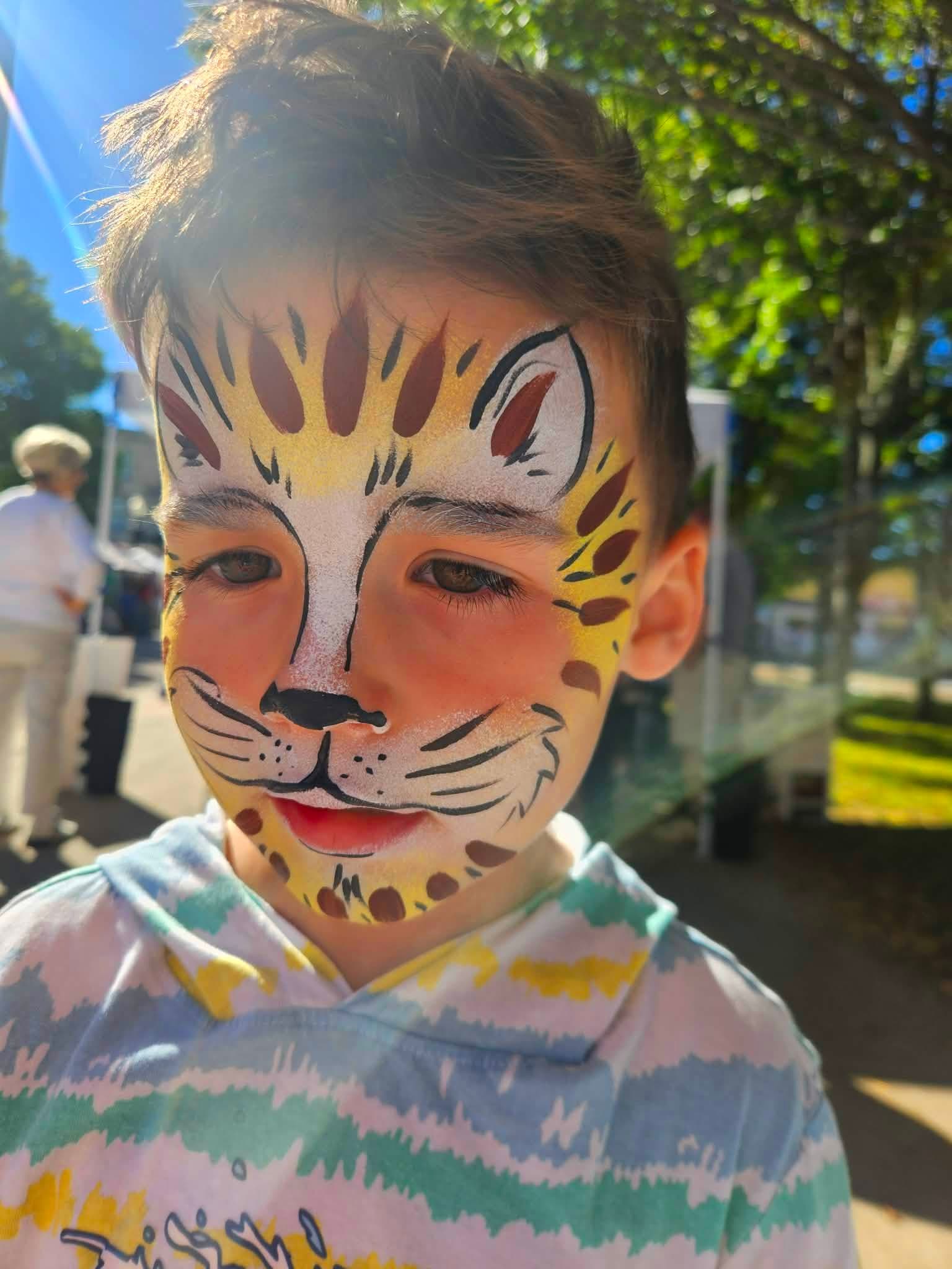 Boy with a yellow spotted leopard face paint design with whiskers