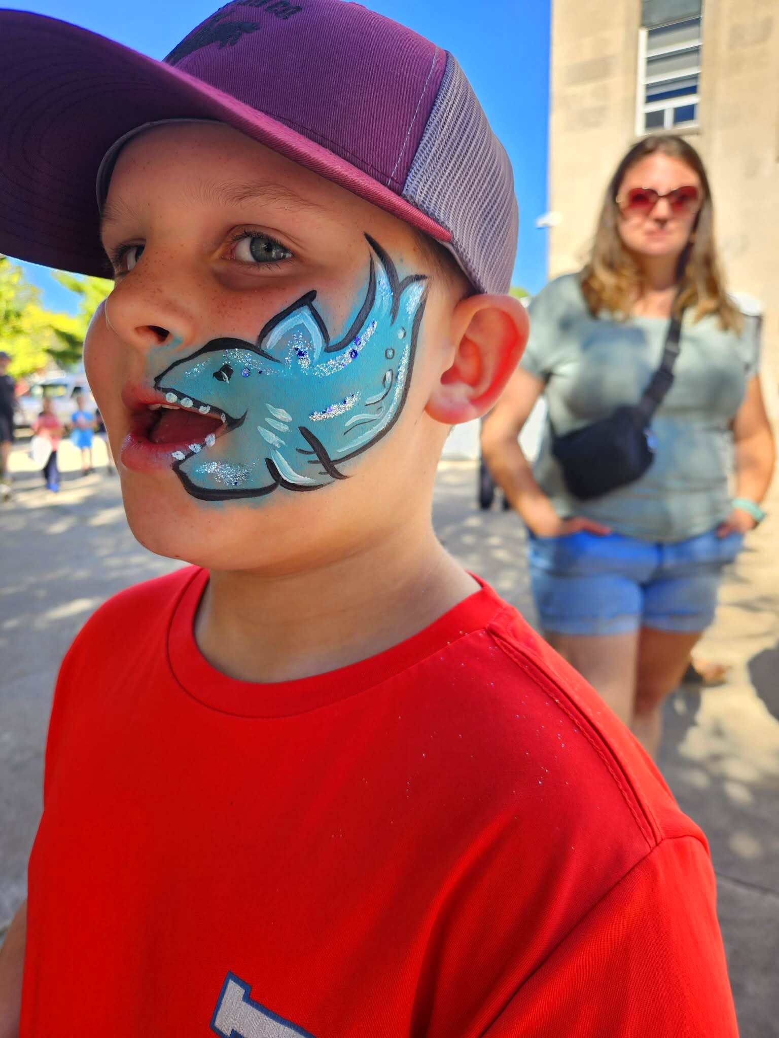 Boy with a blue shark with sparkly fins painted on his cheek