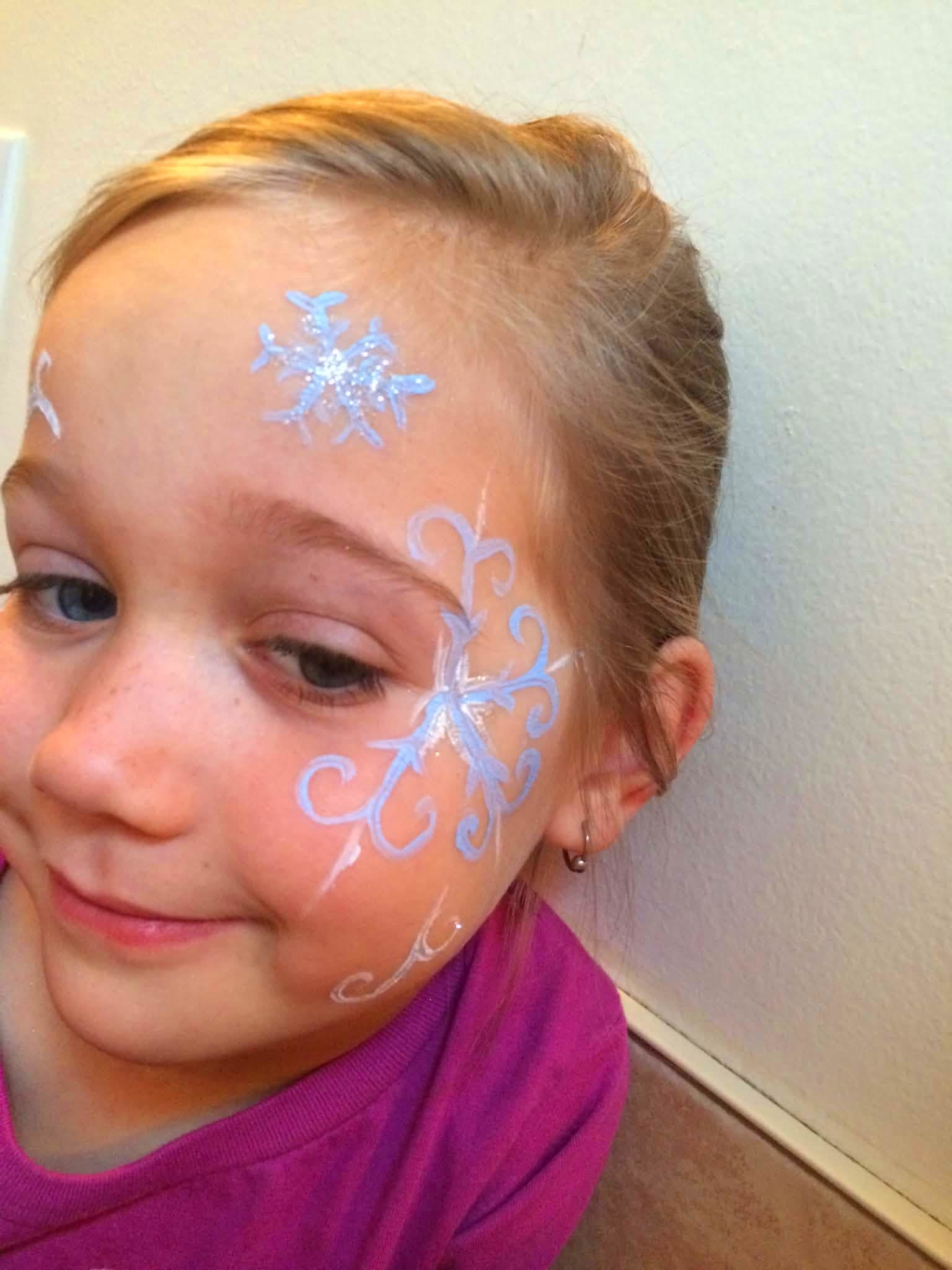 Girl with sparkling white winter snowflakes painted on her forehead and cheek