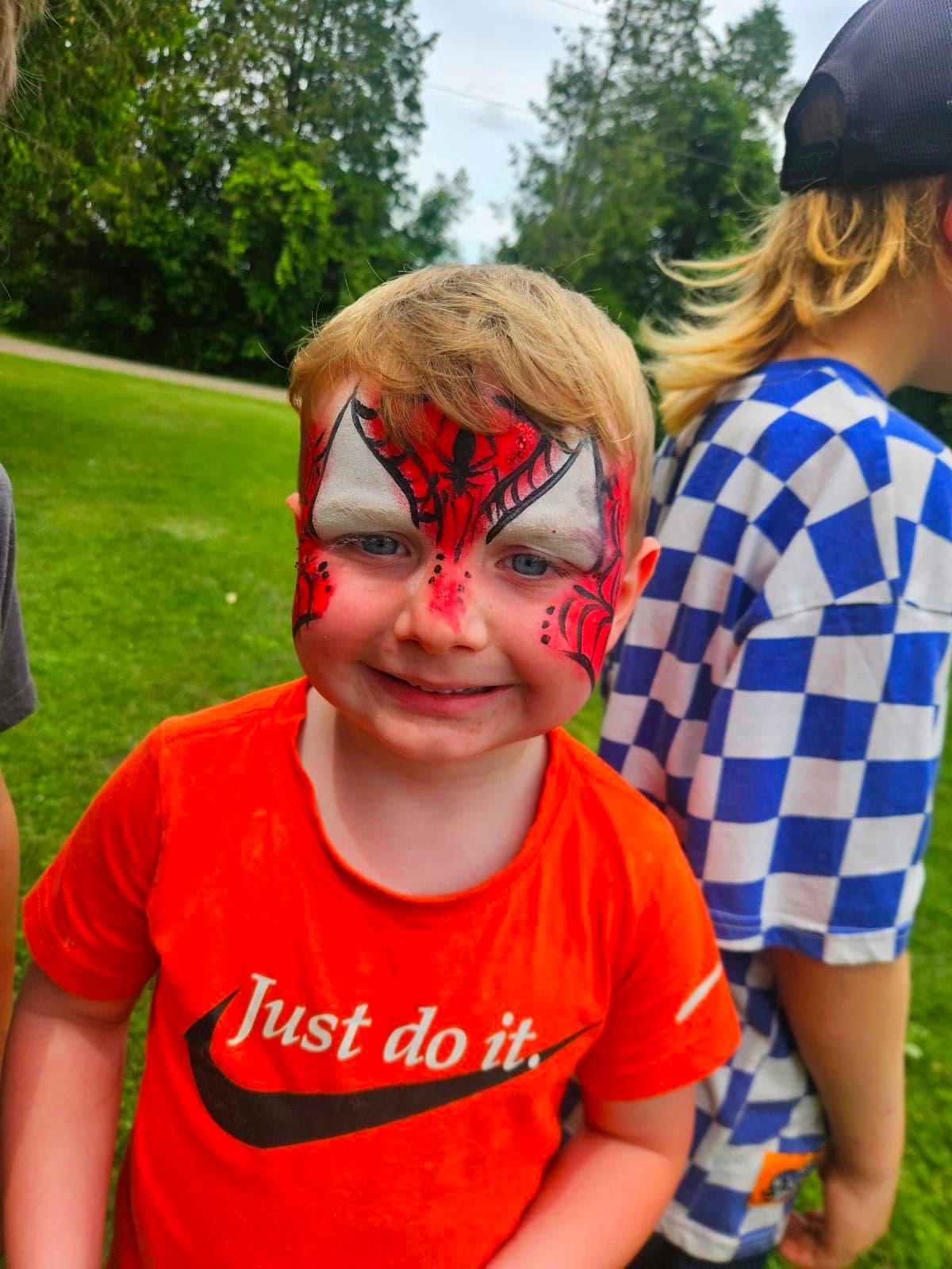 Boy with a red Spiderman mask design painted across his eyes and forehead