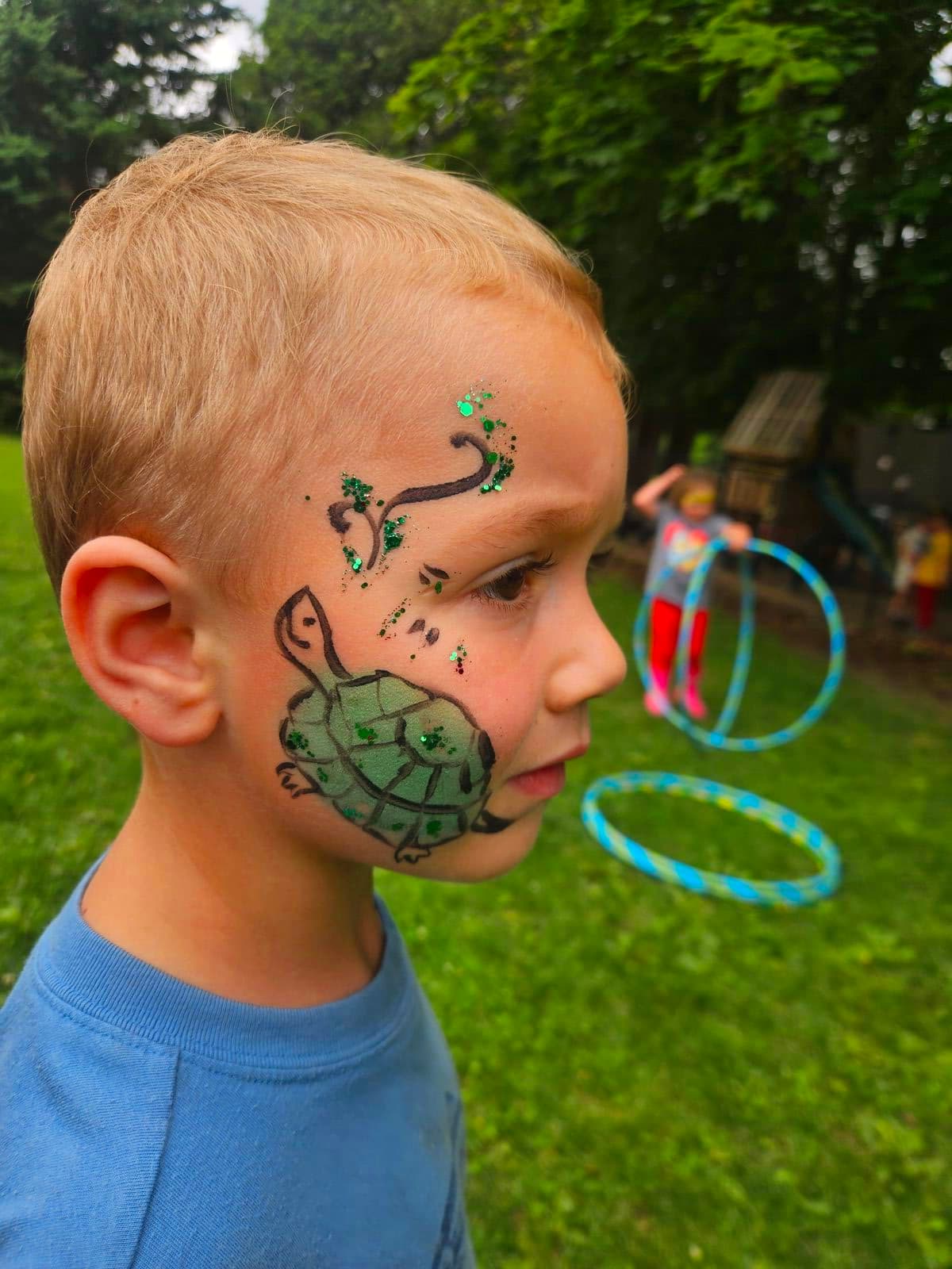 Boy with a green turtle painted on his cheek