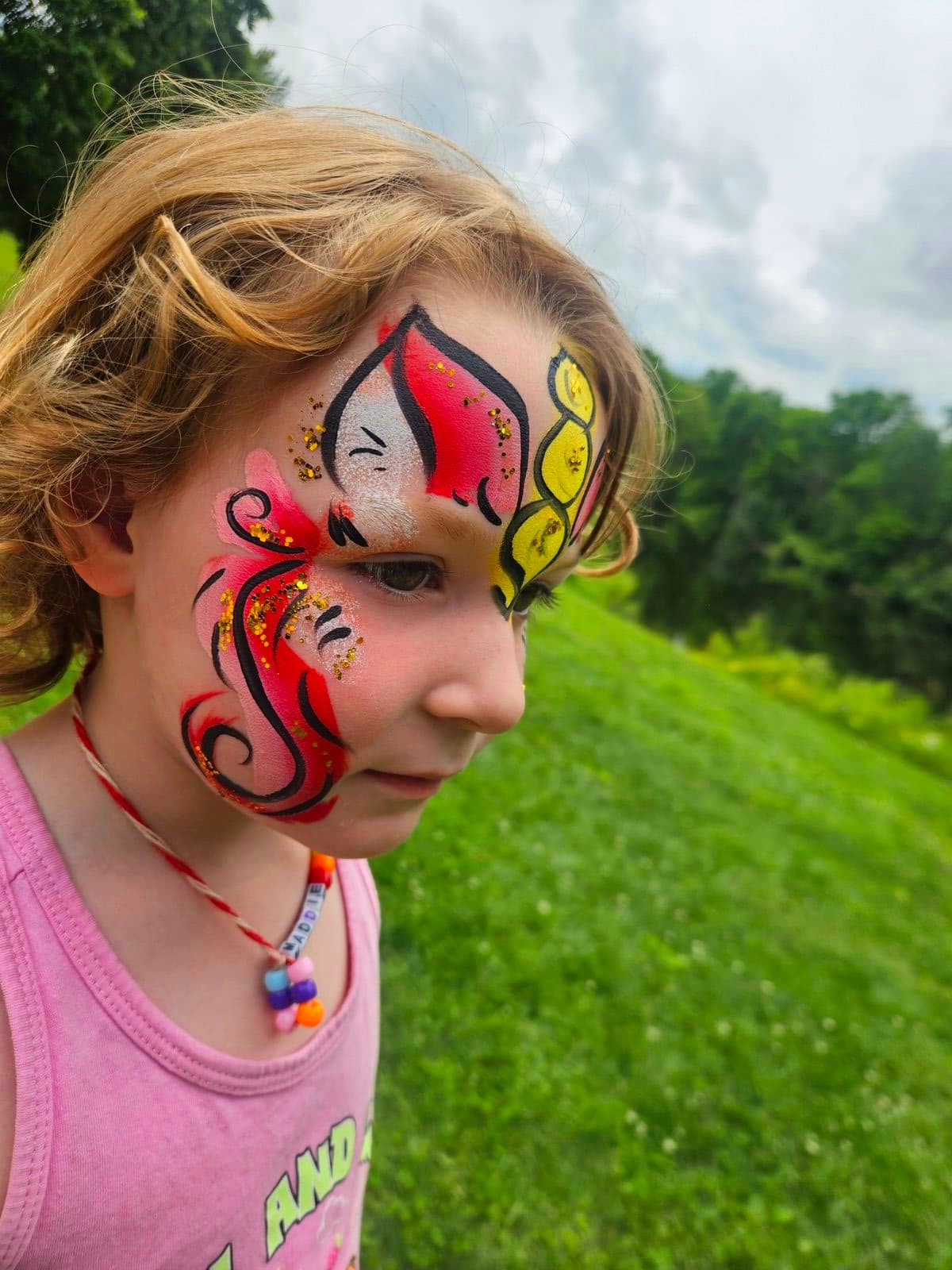 Profile of a girl with golden unicorn horn and pink swirl face paint