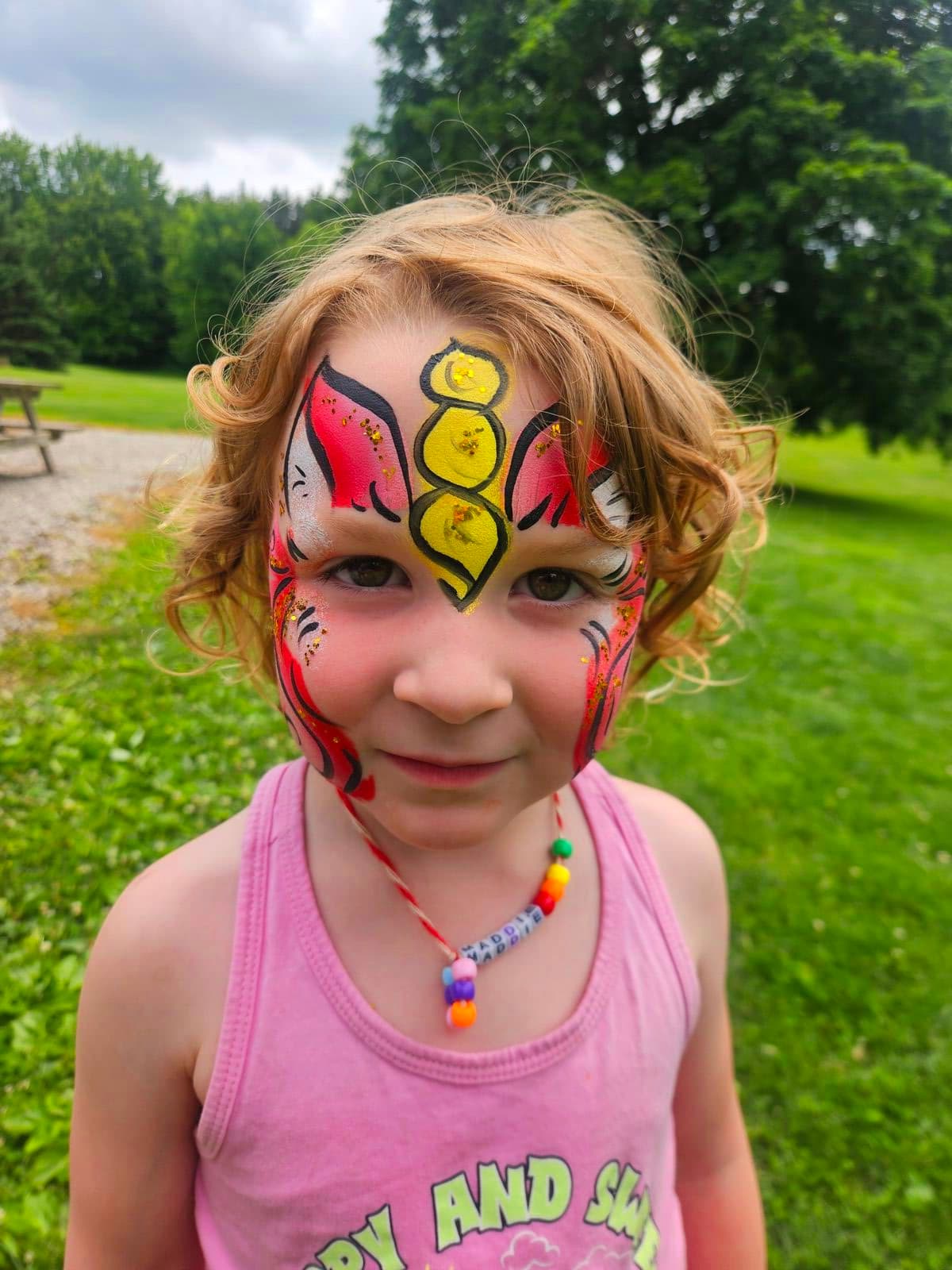 Girl with a golden unicorn horn and pink swirl face paint
