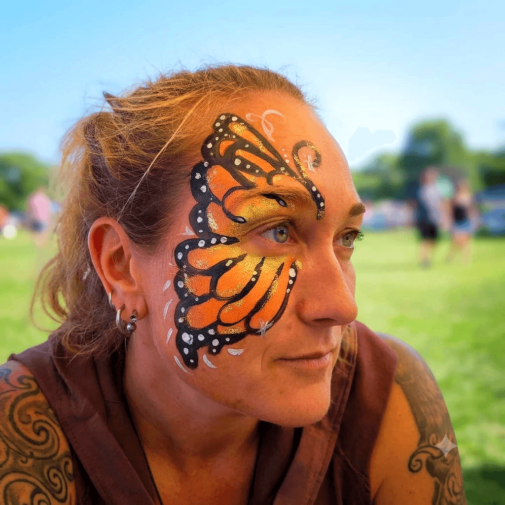 Roz, the artist behind Crafty Q Face Painting, wearing a monarch butterfly face paint design